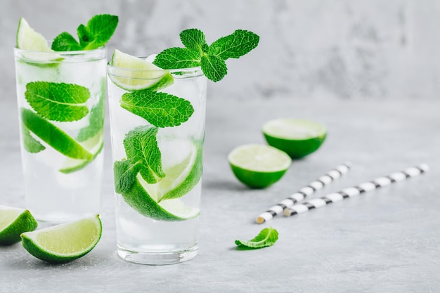 Koktajl Mojito z lodową świeżą miętą i limonką w szkle na szarym kamiennym tle Orzeźwiający lodowaty letni napój