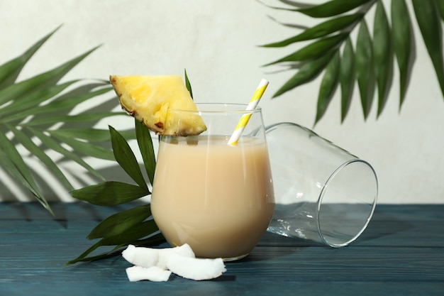 Koktajl pina colada na niebieskim drewnianym stole.