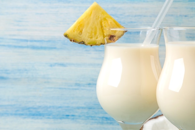 Koktajl Pina Colada. Pina Colada orzeźwiający letni koktajl alkoholowy z mlekiem kokosowym i sokiem ananasowym w pobliżu. letni napój. przygotowanie koktajlu. na niebieskim drewnianym stole. zbliżenie