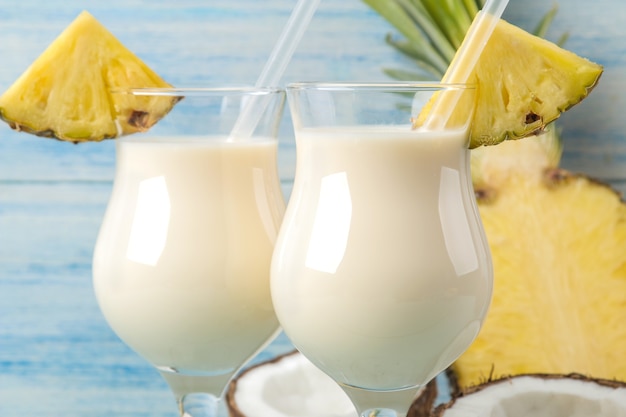 Koktajl Pina Colada. Pina Colada orzeźwiający letni koktajl alkoholowy z mlekiem kokosowym i sokiem ananasowym w pobliżu. letni napój. przygotowanie koktajlu. na niebieskim drewnianym stole.