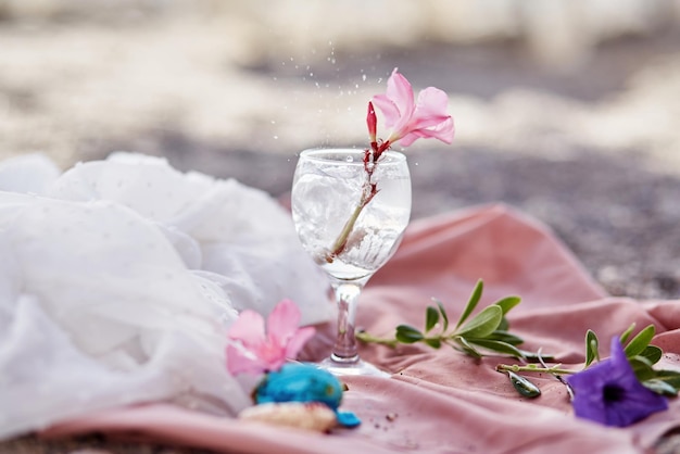Koktajl z tonikiem ginu w kieliszku do wina na plaży z surrealistycznymi kwiatami i makaronikami Delikatne materiały jedwabne i tło bokeh Orzeźwiające lato koncepcja Wysokiej jakości zdjęcie