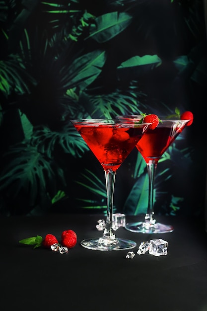 Koktajle malinowe z czerwonym alkoholem w szkle martini na tropikalnym tle Selektywna ostrość