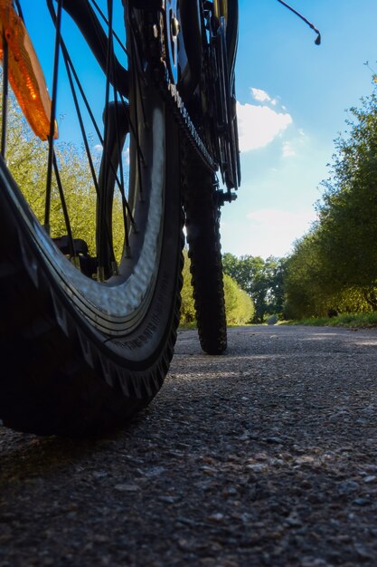 Koła Rowerowe Jeżdżące Po Asfaltowej Drodze Na Tle Błękitnego Jasnego Nieba