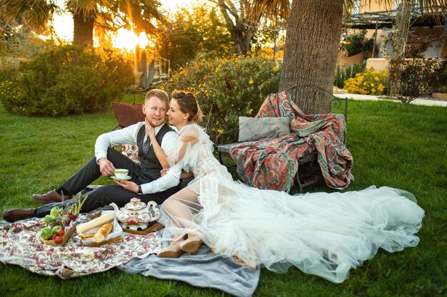 Kolacja nowożeńców na trawniku o zachodzie słońca.Para siedzi i pije herbatę o zachodzie słońca we Francji