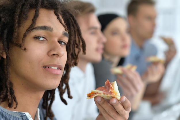 Koledzy robią sobie przerwę w biurze jedząc pizzę