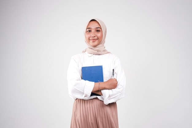 Kolegium Muslimah niosące książkę i długopis do studiowania na białym tle