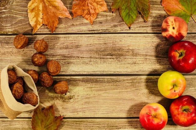 Kolekcja piękne kolorowe jesienne liście orzechy włoskie i jabłka na podłoże drewniane