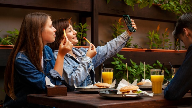 Zdjęcie koleżanki biorąc selfie mając frytki