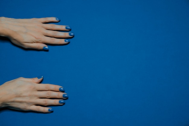 Kolor roku 2020. Piękne, wypielęgnowane paznokcie kobiety z klasycznym niebieskim lakierem do paznokci