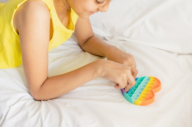 Kolorowa antystresowa zabawka sensoryczna fidget push pop w rękach dziecka. Pop to zabawka