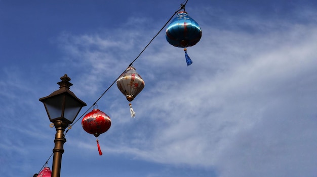 Kolorowa chińska latarnia wisząca na kablu z niebieskim tle nieba
