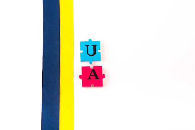 Kolorowa niebiesko-żółta wstążka z tkaniny i puzzle z literami Ukraina na białym tle Symbol państwa