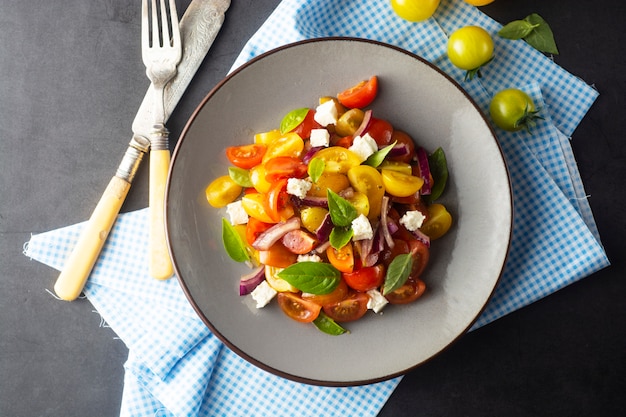 Kolorowa pomidorów i basilu sałatka na talerzu. Zdrowe, letnie jedzenie.