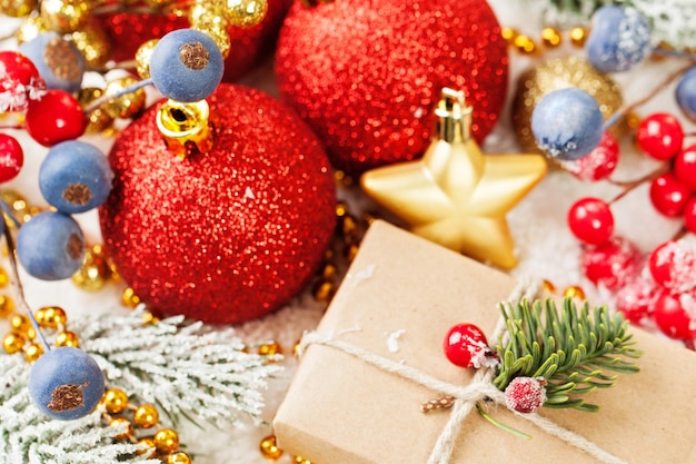 Kolorowa świąteczna kompozycja z prezentowymi czerwonymi bombkami holly jagodami Gałąź drzewa bożonarodzeniowego i złotą girlandą na białym tle śniegu