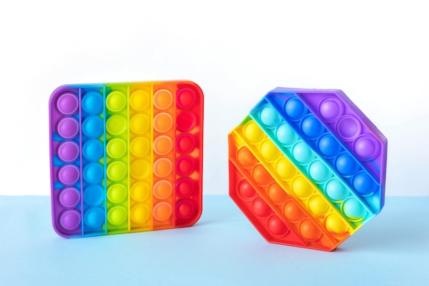 Kolorowe antystresowe fidget push pop to zabawki sensoryczne dla dzieci na białym tle na niebieskim tle. Prosty dołek. Widok z góry, układ płaski. Selektywne skupienie.