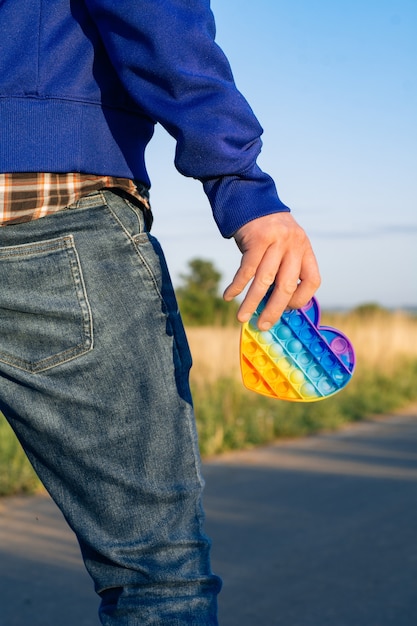 Zdjęcie kolorowe antystresowe zabawki sensoryczne fidget push pop go w dłoni człowieka. mężczyzna idzie z zabawką pop it