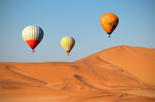 Kolorowe balony na ogrzane powietrze latające nad wydmami o zachodzie słońca. Afryka, Namibia