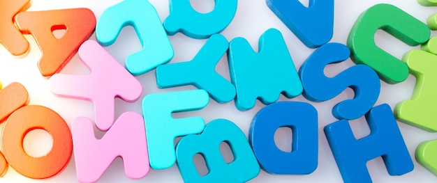 Kolorowe bloki liter alfabetu rozrzucone losowo na białym tle