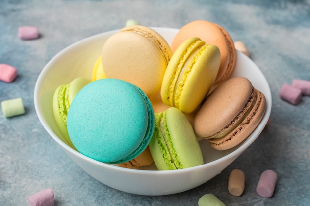 Kolorowe ciasteczka macarons na talerzu i przewiewne pianki