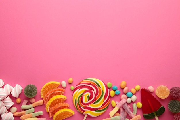 Kolorowe cukierki lizaki i galaretki na różowym tle. Widok z góry. Słodycze z miejscem na kopię