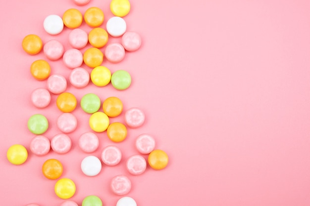 Kolorowe cukierki na różowym tle