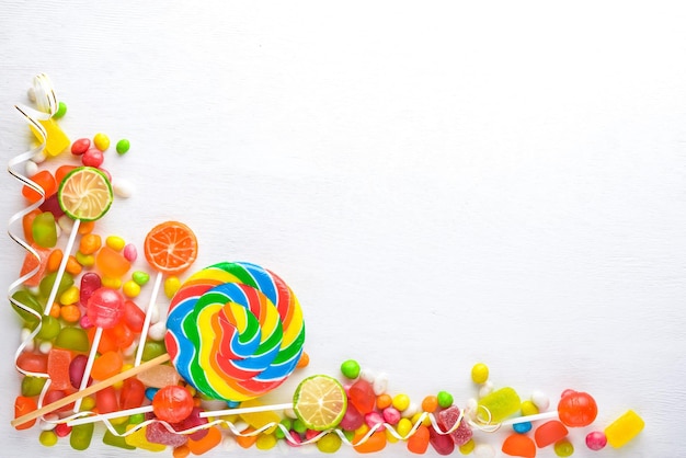 Kolorowe cukierki słodycze i lizaki Na białym drewnianym tle Widok z góry Wolne miejsce
