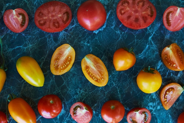 Kolorowe czerwone, pomarańczowe i żółte pomidory na zielonym marmurowym tle Naturalna żywność ekologiczna Jedzenie z widokiem z góry