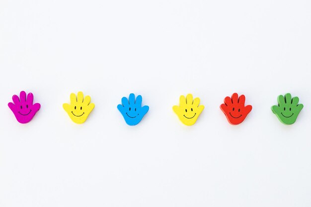Kolorowe drewniane figurki w formie dłoni z uśmiechami na białym tle