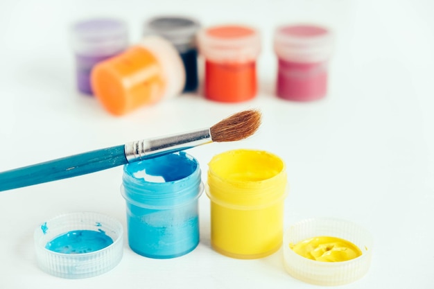 Zdjęcie kolorowe farby gwaszowe i pędzel do malowania na białym drewnianym stole. kopiuj, puste miejsce na tekst