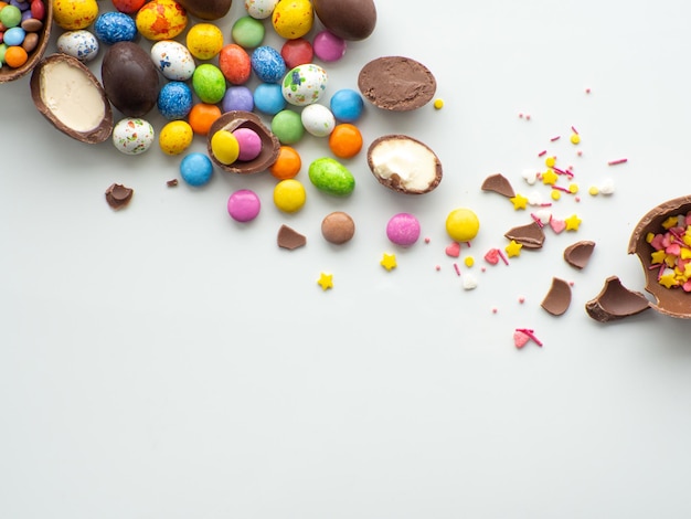 Kolorowe i czekoladowe pisanki ze słodką drażetką na białym tle