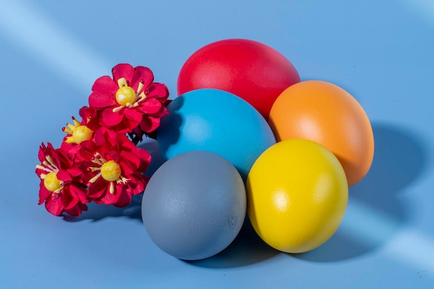 Kolorowe jajka symbolizujące Wielkanoc na kolorowym tle i kwiatach