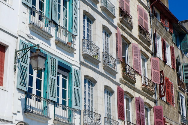 Kolorowe klasyczne fasady z okiennicami i malutkimi balkonami w centrum Bayonne French Basque