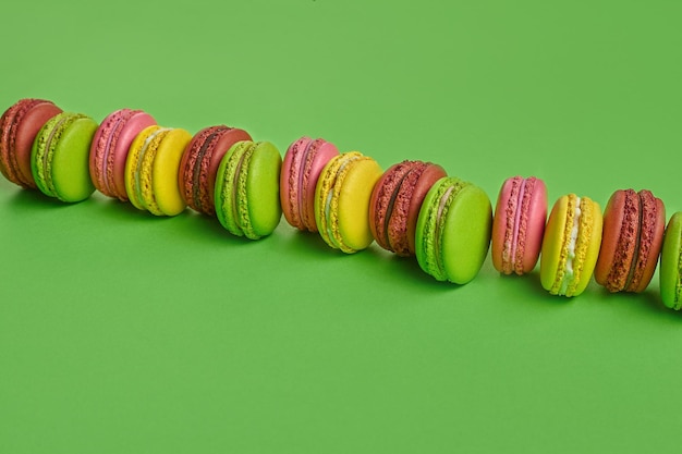 Zdjęcie kolorowe macaron lub macaroon słodkie słodycze na bazie bezy na zielonym tle przestrzeń kopiowania przeznaczone do walki radioelektronicznej