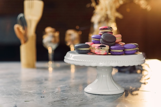 Kolorowe macarons na białej tacy na marmurowym stole z serwetką i akcesoriami kuchennymi