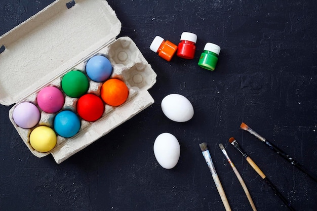 Kolorowe malowane jaja wielkanocne w pudełku na jaja ozdobione wiórkami na czarnym tle