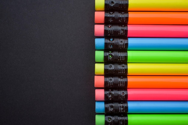 Kolorowe ołówki z gumką na czarnym tle. Kilka kolorowych kredek.