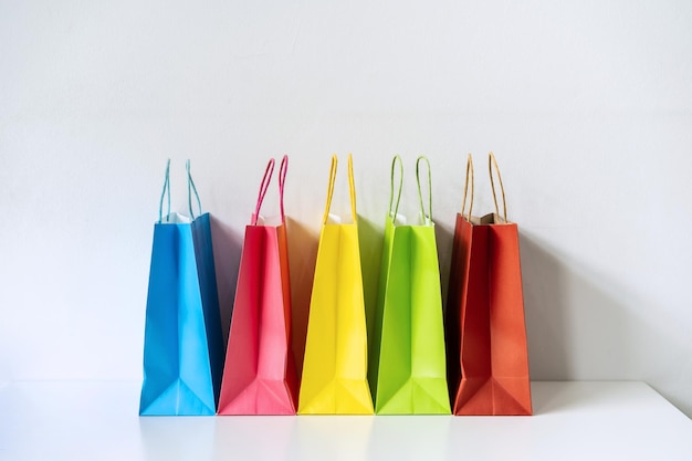 Zdjęcie kolorowe papierowe torby na zakupy na białym stole i tle z miejscem na kopię