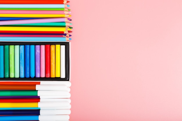 Kolorowe pastele ołówki pisaki na różowym tle koncepcja szkoły rysunku lub hobby dla dzieci kopiowanie miejsca na tekst