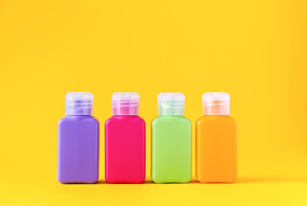 Kolorowe plastikowe butelki na produkty do pielęgnacji skóry lub do różnych celów na żółtym tle