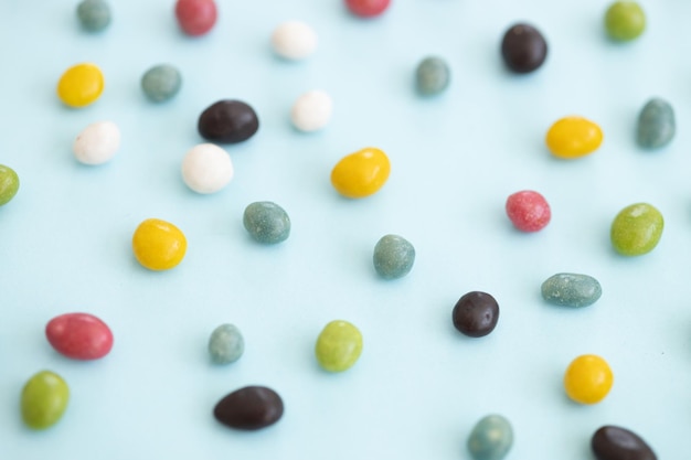 Kolorowe powlekane cukierki czekoladowe rozrzucone na niebieskim tle