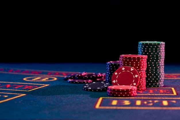 Kolorowe stosy żetonów stojące na niebieskiej okładce stołu do gry na czarnym tle hazard rozrywka