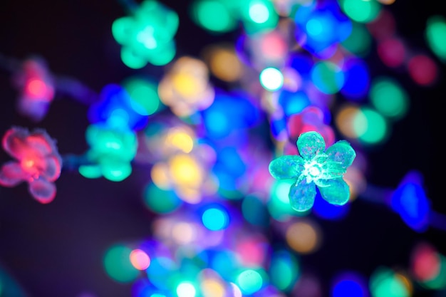 Kolorowe światła bokeh z dekoracyjnych girland świecących kwiatów na wakacyjnych wielobarwnych światłach