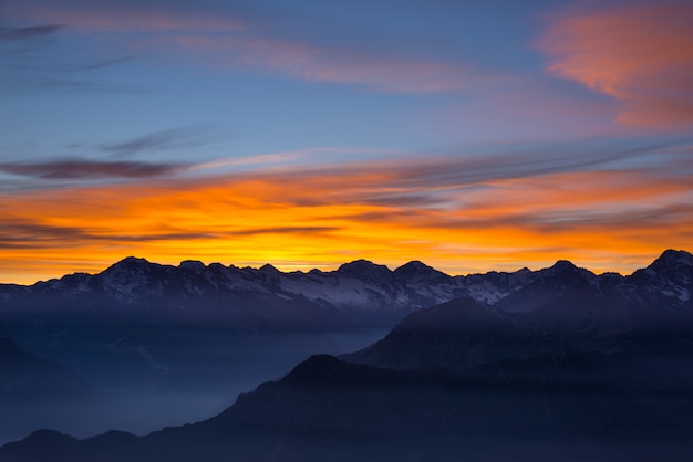 Kolorowe światło słoneczne za majestatycznymi szczytami włoskich Alp Francuskich