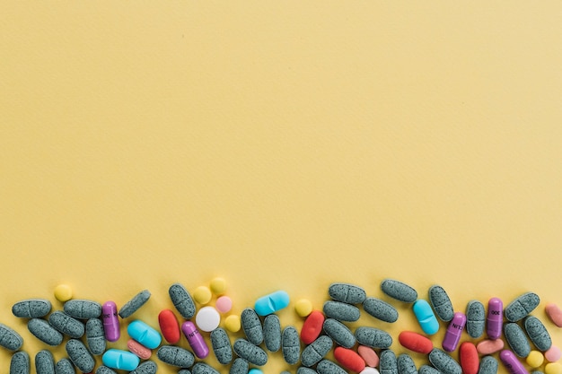 Kolorowe tabletki u dołu na żółtym tle