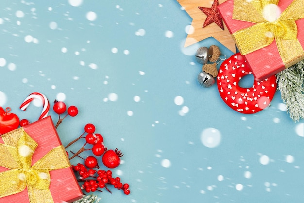 Kolorowe tło Boże Narodzenie. Świąteczna kompozycja świąteczna z czerwonymi jagodami ostrokrzewu, prezentami i zieloną gałęzią jodły na niebieskim tle