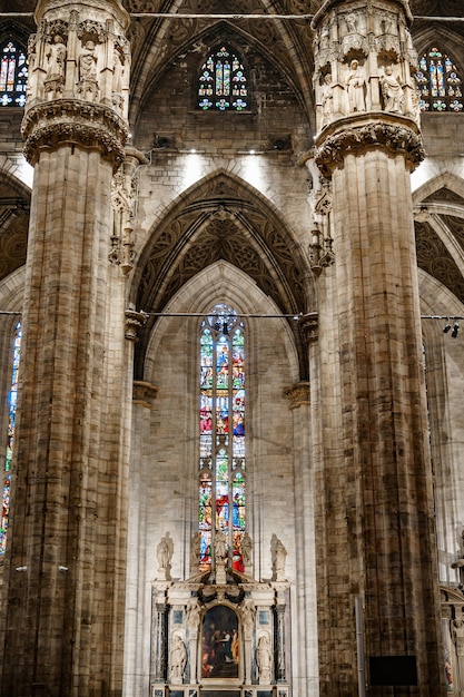 Kolorowe witraże na tle ogromnych rzeźbionych marmurowych kolumn katedry we włoszech mediolan