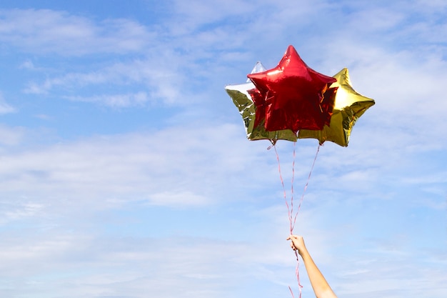 Kolorowe złote błyszczące balony w kształcie gwiazdy na niebie z chmurami