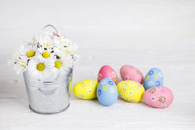 Kolorowi Easter jajka i bukiet stokrotki na białym drewnianym stole.