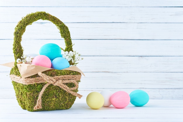 Kolorowi Easter jajka w koszu na białym drewnianym tle