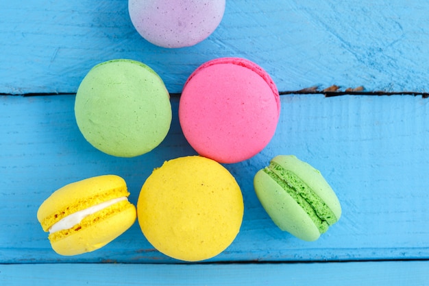 Kolorowi macaron ciastka na błękitnym drewnianym rocznika stole